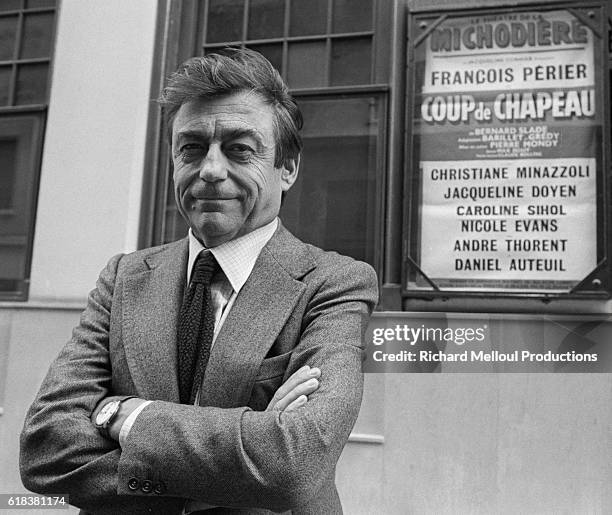 French actor Francois Perier stands near a poster advertising the play Coup de Chapeau. Perier appears in the play directed by Pierre Mondy. Other...