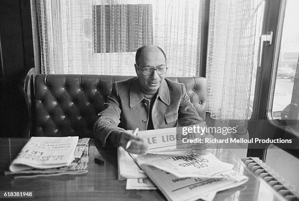 Serge Dassault, head of Dassault Aviation, reads a daily newspaper in a cafe.