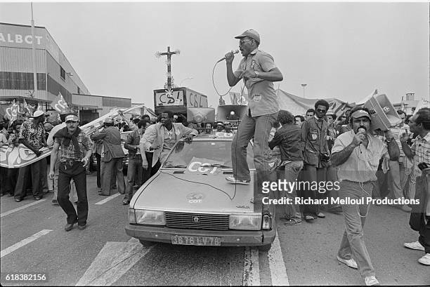 Worker from the Confederation Generale de Travail trade union speaks to the crowd from the hood of a car during a strike outside the Talbot car plant...