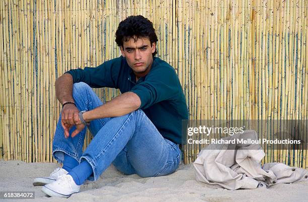 French actor Anthony Delon sits in the sand. He was in Cannes to attend the 40th Cannes Film Festival.