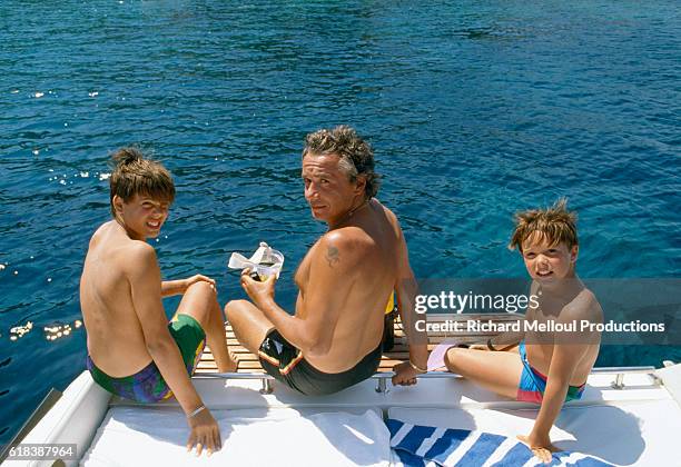 French singer and actor Michel Sardou on the back of a boat with his two sons Gary and Romain while on holiday in St. Tropez, France.