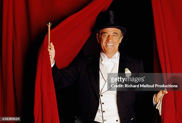 French actor Jean-Paul Belmondo emerges from a curtain dressed in a tuxedo for his role in the Georges Feydeau play Tailleur pour les Dames.