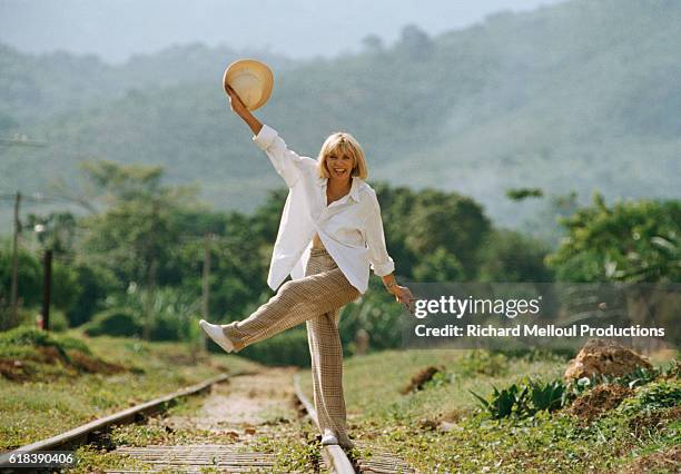 French actress Mireille Darc walks along railroad tracks on the set of the 1996 mini series Terre Indigo.