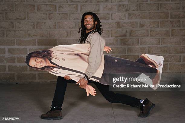 French tennis player Yannick Noah carries a cardboard cutout of himself. The cutout is promoting Noah's new clothing collection.