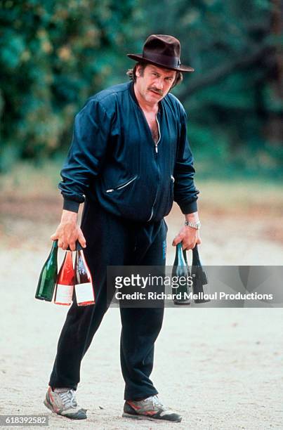 Gerard Depardieu, nominated for the 1991 Best Actor Academy Award, carries bottles of wine in his vineyard, Chateau de Tigne.