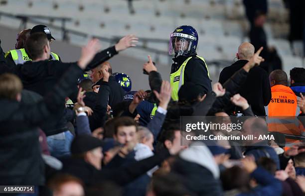 Police officer in riot uniform keeps an eye on the fans as they taunt each other during the EFL Cup fourth round match between West Ham and Chelsea...