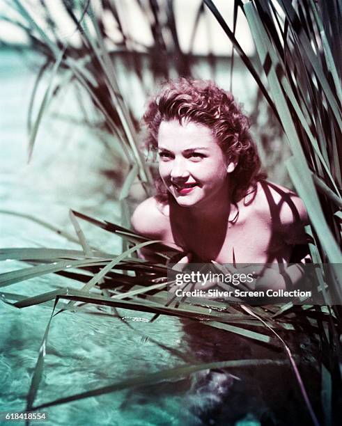 American actress Anne Baxter hides naked in the reeds, circa 1950.