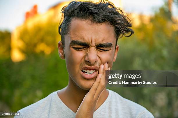 歯痛のために彼の口をこすって心配10代の少年 - 歯痛 ストックフォトと画像