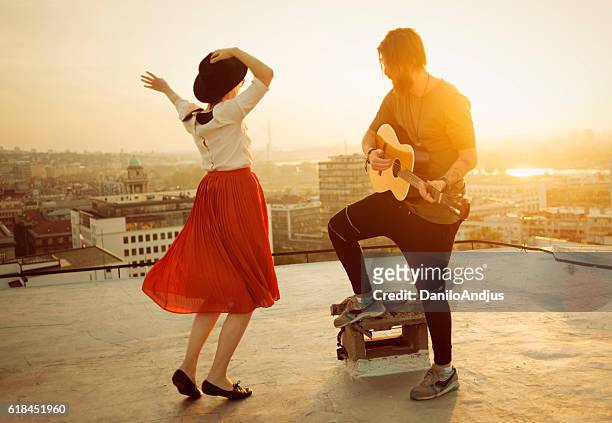 couple dancing on the roof playing the guitar on sunset - pop artist stock pictures, royalty-free photos & images