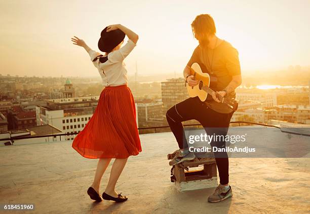 couple dancing on the roof playing the guitar on sunset - pop musician bildbanksfoton och bilder