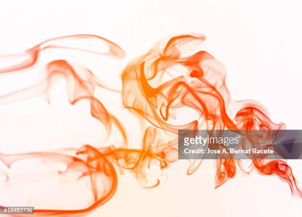 figures and forms of orange smoke in movement on a white bottom - coloured smoke stock-fotos und bilder