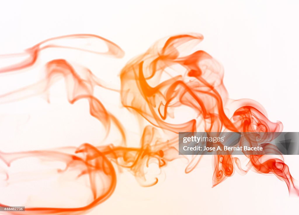 Figures and forms of orange smoke in movement on a white bottom