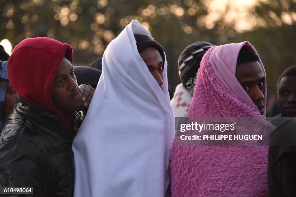 Migrants queue outside an aid station, to be assigned to one of the processing centres across France, near the "Jungle" migrant camp in Calais,...