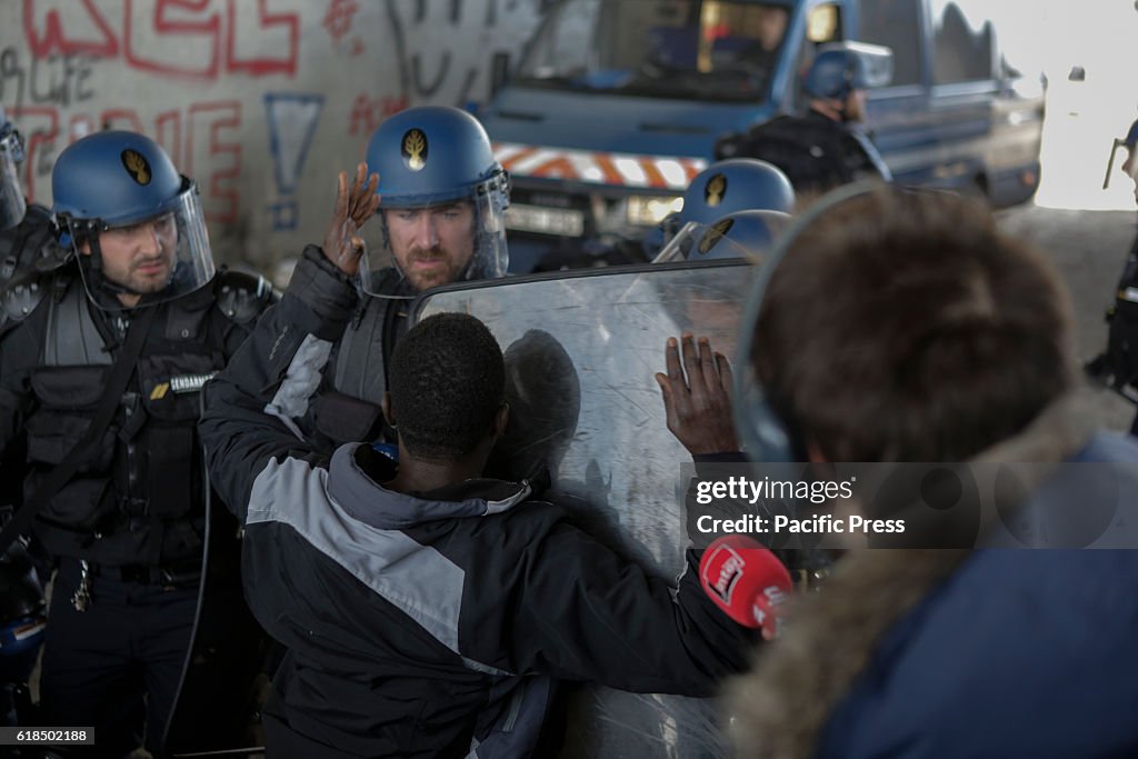 A refugee argues with an police officer about getting access...