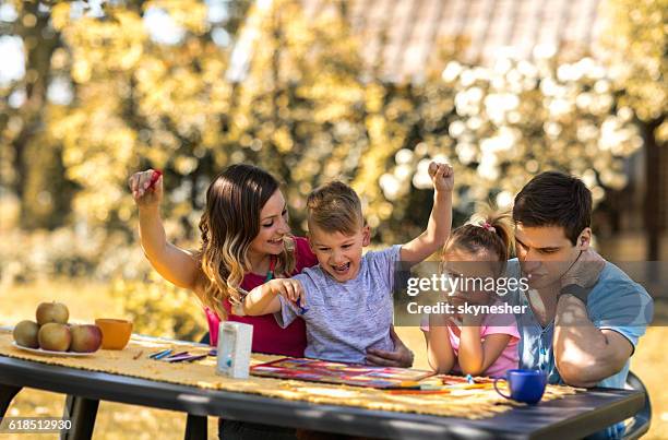 junge eltern und kinder spielen brettspiel im hinterhof. - familie brettspiel stock-fotos und bilder
