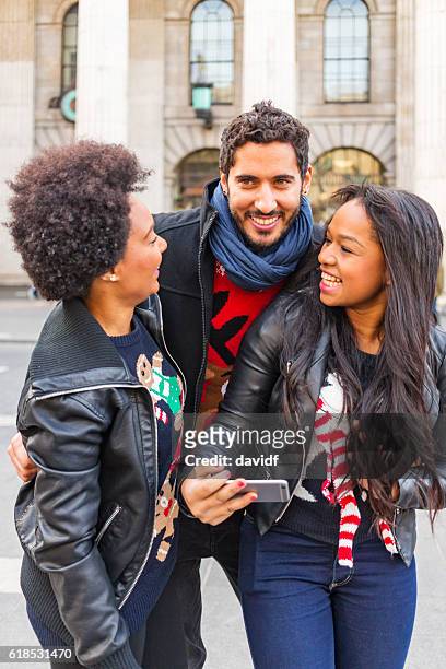 friends taking selfie while christmas shopping in ugly festive sweaters - daily life during christmas season in dublin stock pictures, royalty-free photos & images