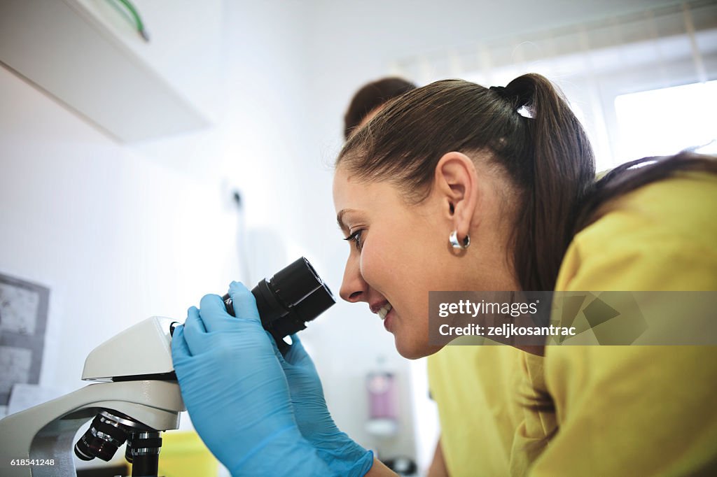 Young scientist working with microscope -