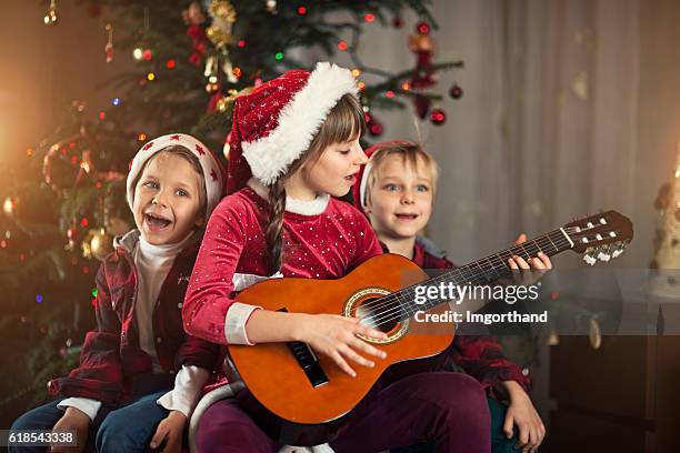 kids singing carols near the christmas tree - christmas music stock pictures, royalty-free photos & images