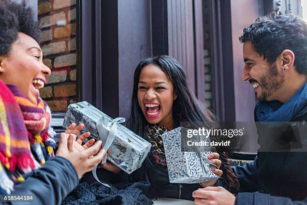 excited young friends exchanging christmas gifts - giving stock pictures, royalty-free photos & images