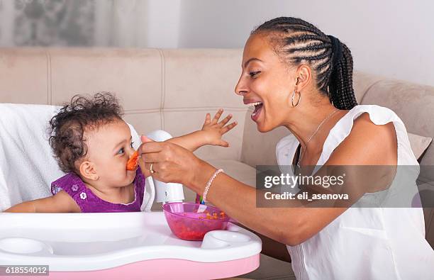 mother spoon feeding her baby - baby feeding stockfoto's en -beelden