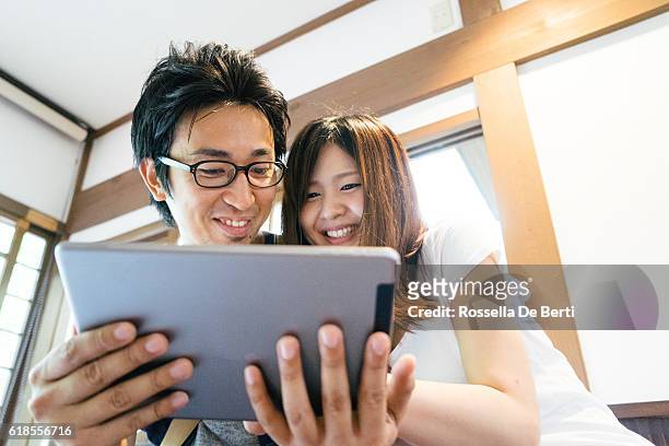 cheerful japanese friends using tablet indoors - de media stock pictures, royalty-free photos & images