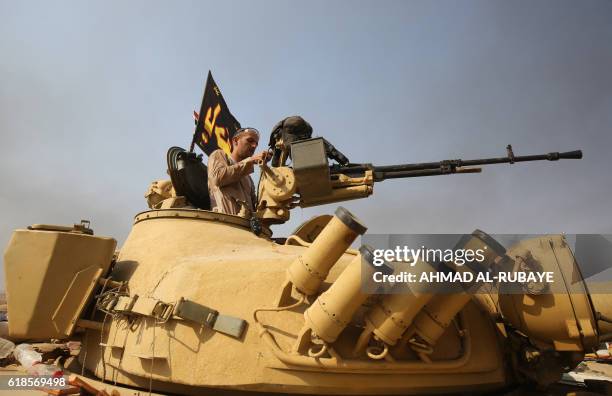 Member of the Iraqi pro-government forces stands on top a T-72 tank as he holds a position near the village of Sin al-Dhuban, south of Mosul, on...