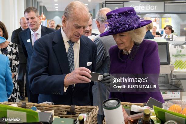 Britain's Prince Philip, Duke of Edinburgh, and Camilla, Duchess of Cornwall look at products in food hampers during a visit to a Waitrose...