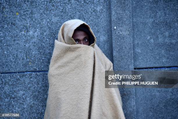 Migrant wrapped in a blanket looks on near the "Jungle" migrant camp in Calais, northern France, on October 27 during a massive operation to clear...