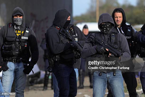 French police clear the main entrance and road into the Calais 'Jungle' migrant camp as the last few remaining migrants leave on October 27, 2016 in...