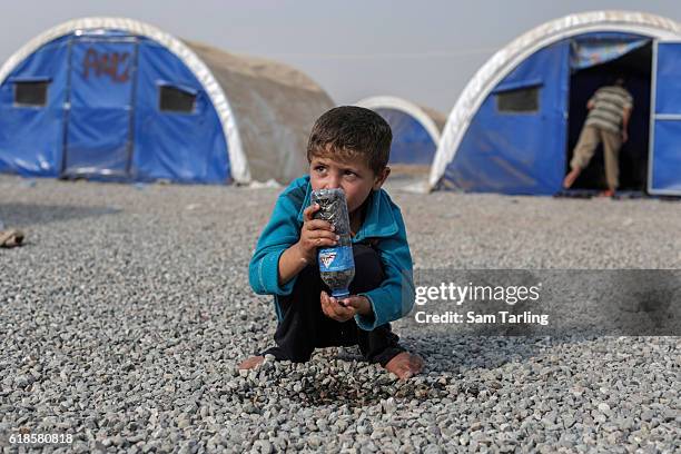 Young child plays with a bottle full of stones at a newly opened camp for people who have been forced to flee their homes due to the current...