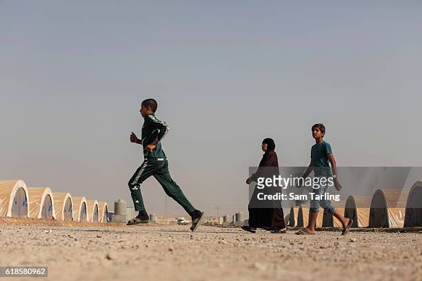 Two boys and a woman walk through a newly opened camp for people who have been forced to flee their homes due to the current offensive on Mosul, on...