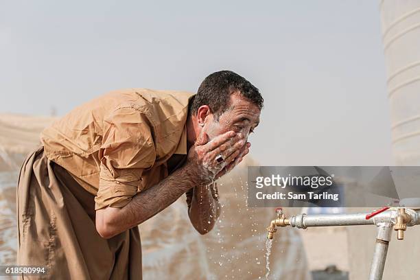 Man from the village of Tob Zawa, which was recently taken from ISIS, washes his face at a water tap-stand in a recently opened camp for people who...