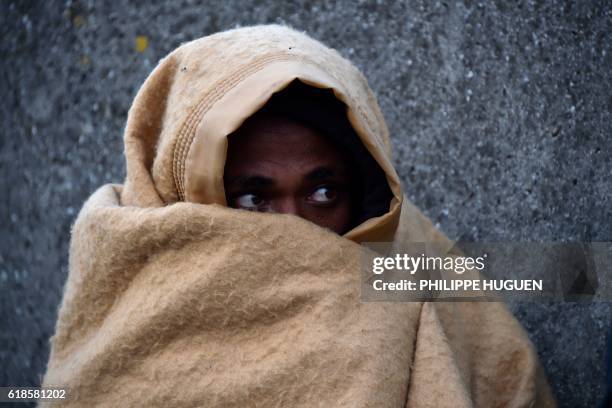 Migrant wrapped in a blanket looks on near the "Jungle" migrant camp in Calais, northern France, on October 27 during a massive operation to clear...