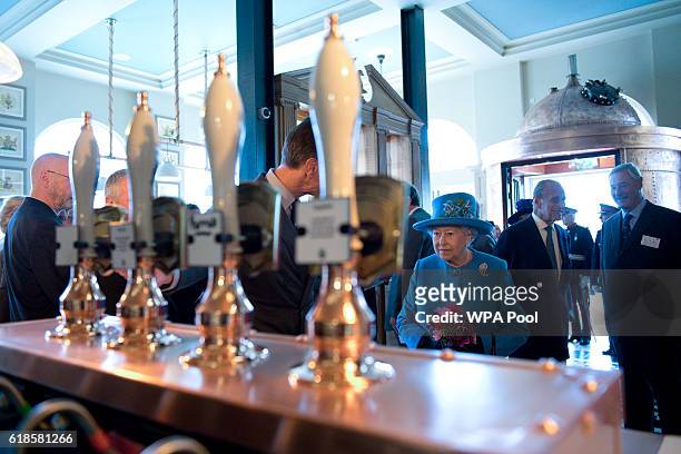Britain's Queen Elizabeth II and Prince Philip, Duke of Edinburgh are pictured inside the Duchess of Cornwall pub on October 27, 2016 in Poundbury,...