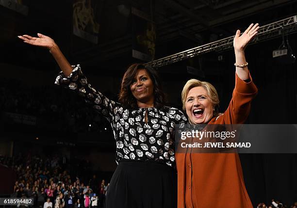 First Lady Michelle Obama and Democratic presidential nominee Hillary Clinton wave during a campaign rally in Winston-Salem, North Carolina on...