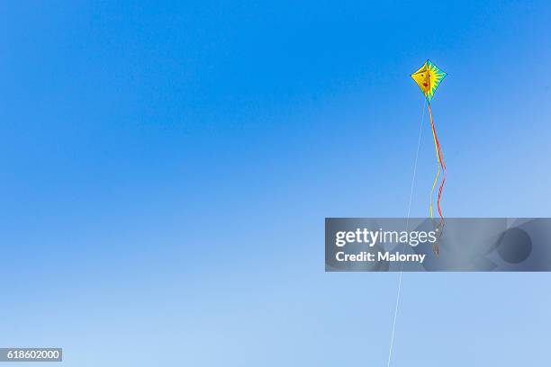 colourful kites flying in the air against blue sky. low angle view. - kite bird stock pictures, royalty-free photos & images