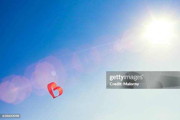 red heart kite or balloon against blue sky. love is in the air. - kite bird stock pictures, royalty-free photos & images