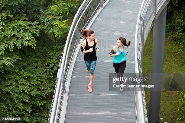 two athletic women running. - asian and indian ethnicities smartwatch phone stock pictures, royalty-free photos & images