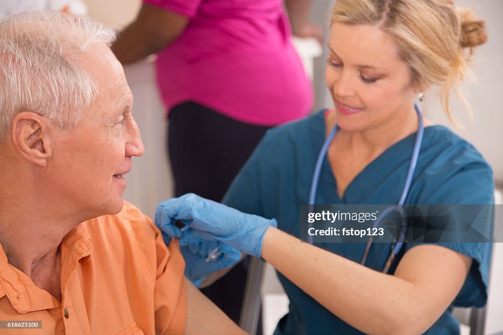 Nurse gives flu vaccine to senior adult patient at pharmacy.