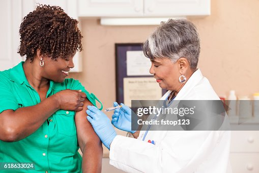 Doctor or nurse gives flu vaccine to patient at clinic. Doctor or nurse gives flu vaccine to patient at clinic.
