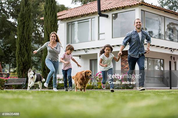 happy family playing with their dogs - apporteren stockfoto's en -beelden
