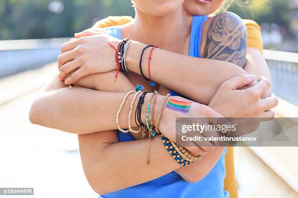 close up of female intertwined hands - gay flag stockfoto's en -beelden