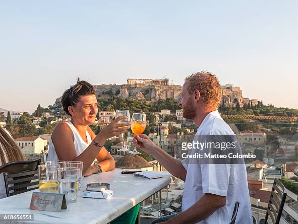 couple drinking near the acropolis. athens, greece - toast around the world celebration stock pictures, royalty-free photos & images