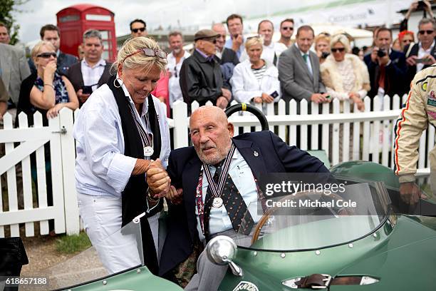 Susie Moss lends a helping hand to Sir Stirling Moss to climb out of the Aston Martin DB3S, owned by Steve Boultbee Brooks, in the Assembly Area at...