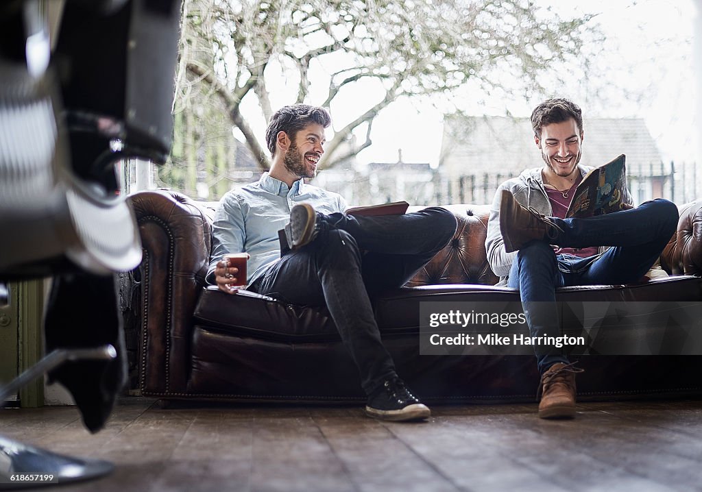 Friends relaxing in waiting area of barber shop.