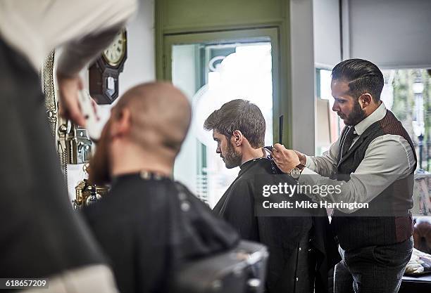 male barber perfecting hair cut - busy barber shop stock pictures, royalty-free photos & images