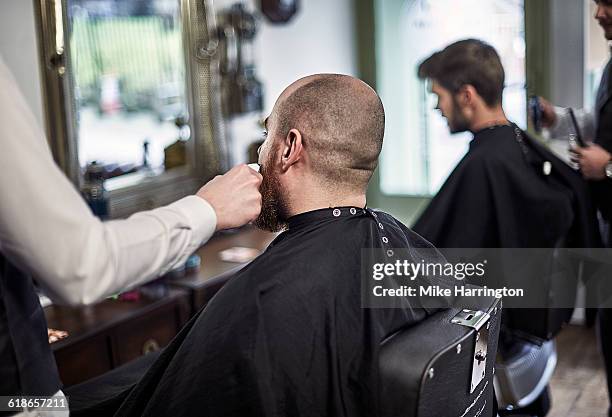young male having beard trim - busy barber shop stock pictures, royalty-free photos & images