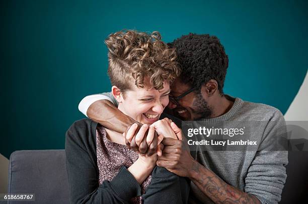 couple with intertwined hands laughing playfully - couple laughing hugging stock pictures, royalty-free photos & images