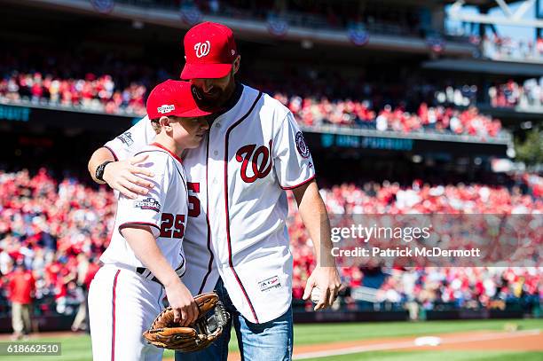 Former MLB player Adam LaRoche embraces his son Drake LaRoche after throwing out the ceremonial first pitch prior to game two of the National League...