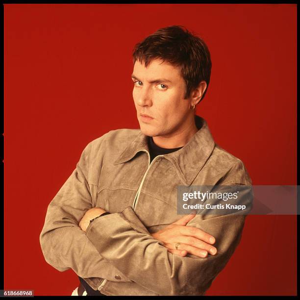 Portrait of British musician Simon LeBon, of the group Duran Duran, as he poses, arms crossed, against a red background, Tokyo, Japan, late 1980s.